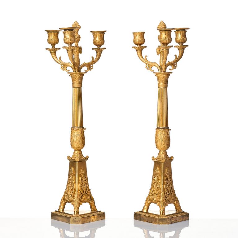 A pair of French Empire three-branch ormolu candelabra, early 19th century.