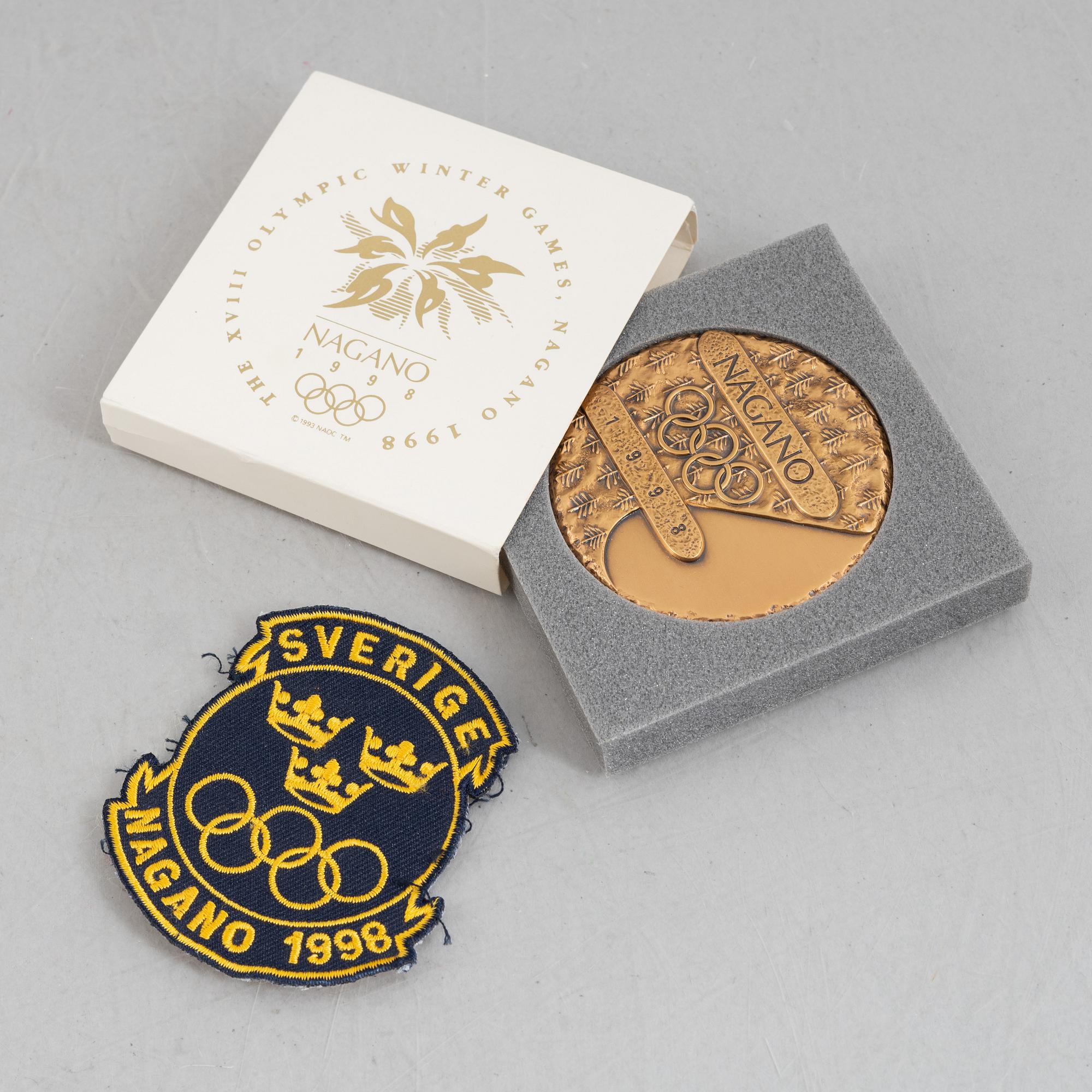 Deltagarmedalj OS Nagano 1998 samt ett tygmärke för den Svenska OS-truppen.