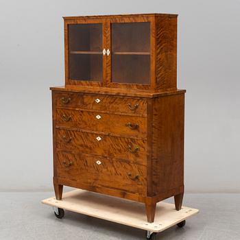 a chest of drawers with a vitrine cabinet from the early 20th century.