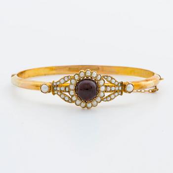 BANGLE, 10K gold, 1 cabochon garnet and seed pearls. 1900s. Hinged mechanism.