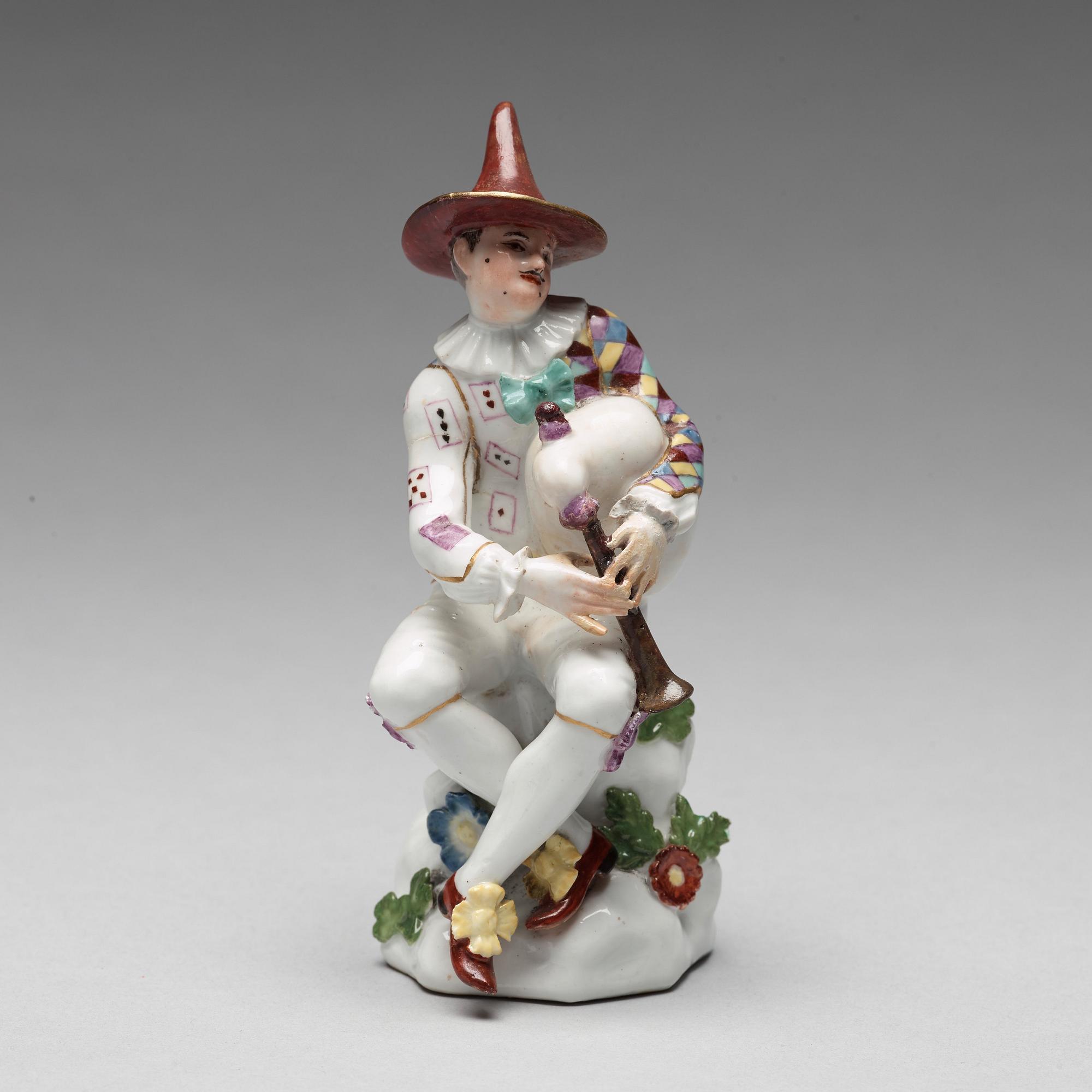 A porcelain figure of harlekin playing the bagpipe, circa 1900.