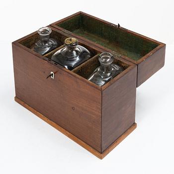 A mahogany-veneered box with glass bottles, around 1800.