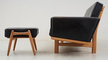 A Hans J Wegner oak and black leather four-seated sofa and stool, Getama, Denmark 1960's.