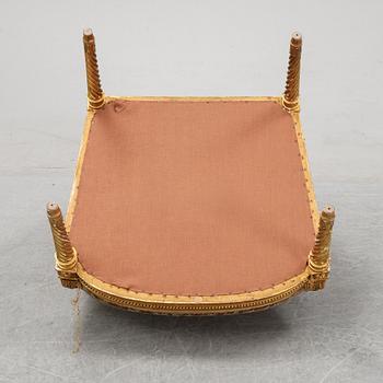 A gilt Louis XVI style armchair from around the year 1900.
