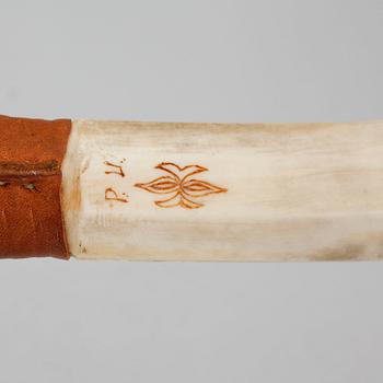 A Sami knife in antler, birch and leather, signed PU, carved dating 1975.