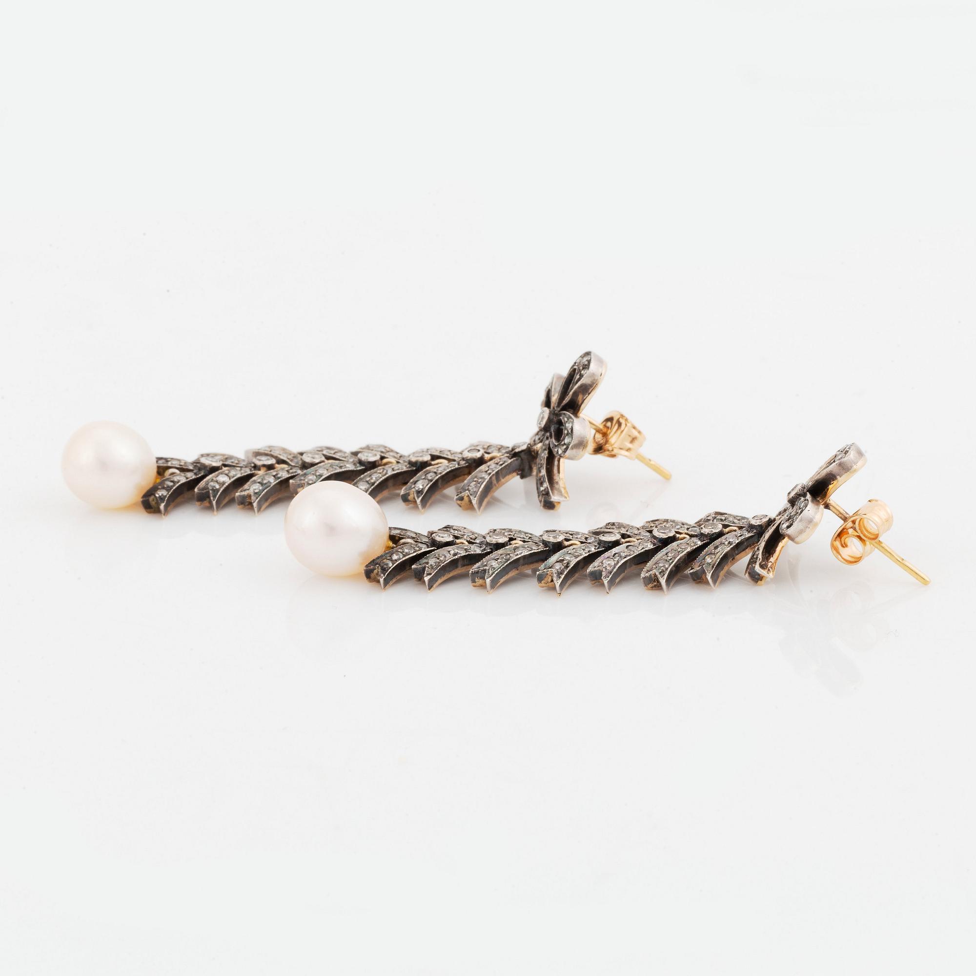A pair of silver and 18K gold earrings with cultured pearls and set with eight-cut diamonds.