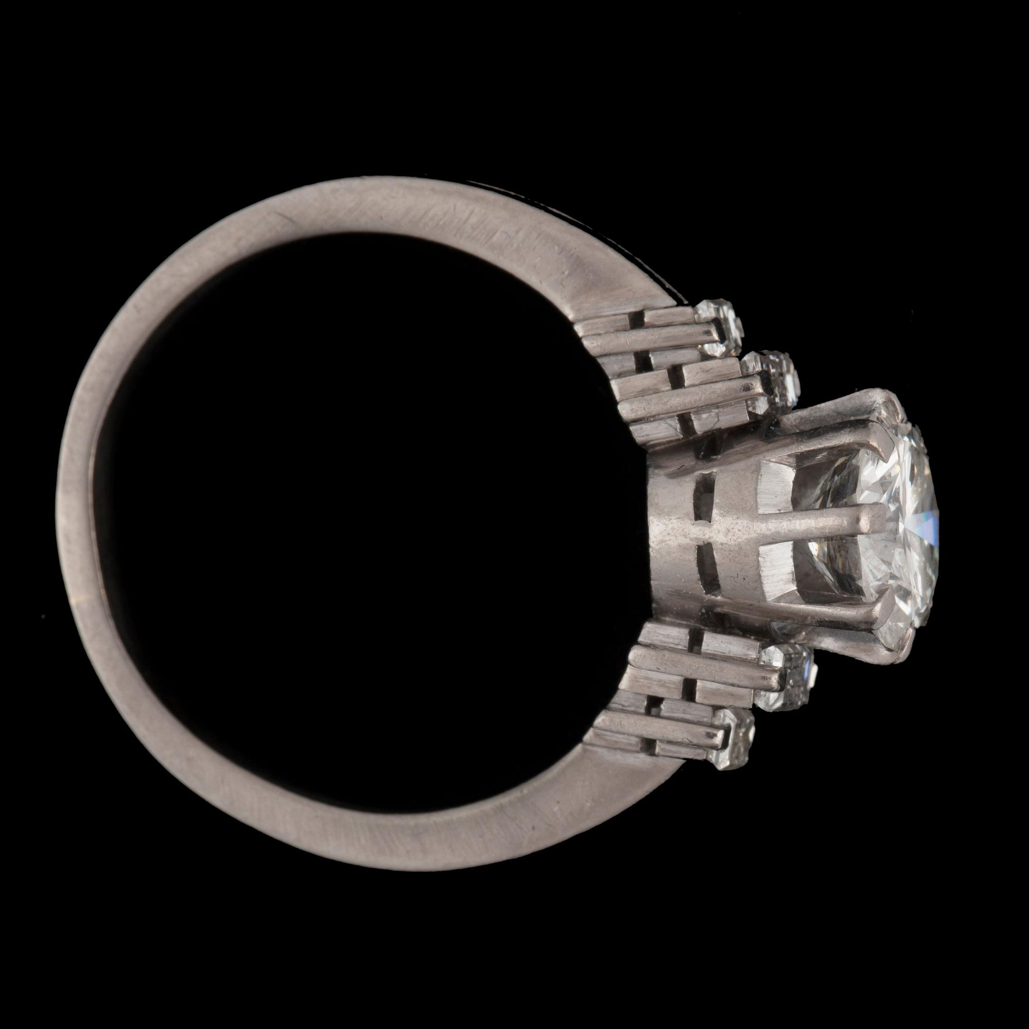 A ring with a brilliant-cut diamond flanked by baguette-cut diamonds. Total carat weights circa 1.80 cts.