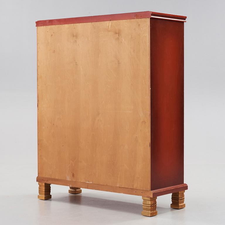 A red lacquered cabinet with carved and bronzed decoration 'à la chinoise', by Otto Wretling, Umeå, Sweden 1930's.