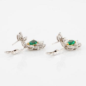 A pair of earrings in 18K white gold with drop-shaped faceted emeralds and diamonds.