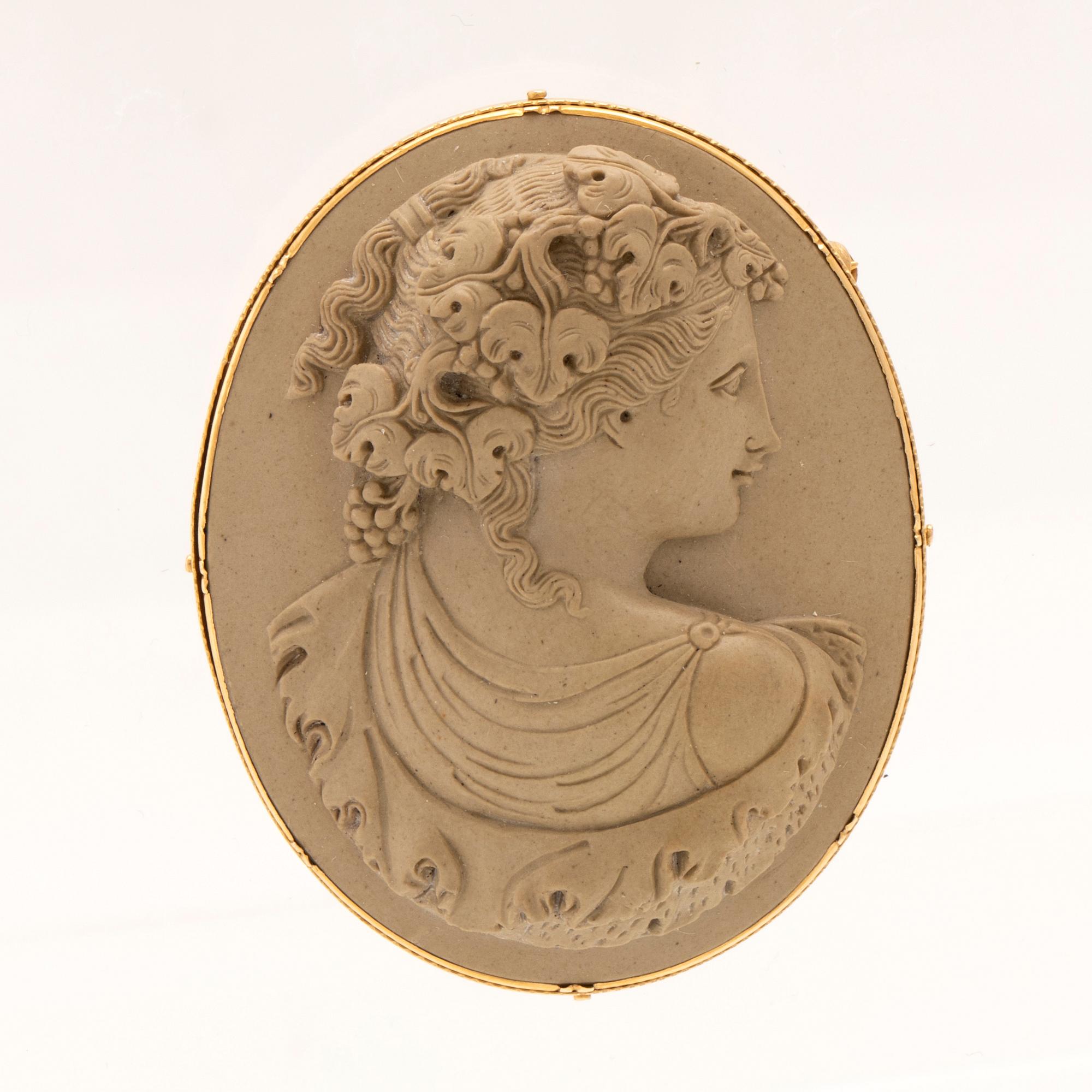 Brosch med lavakamé infattad i 18K guld.