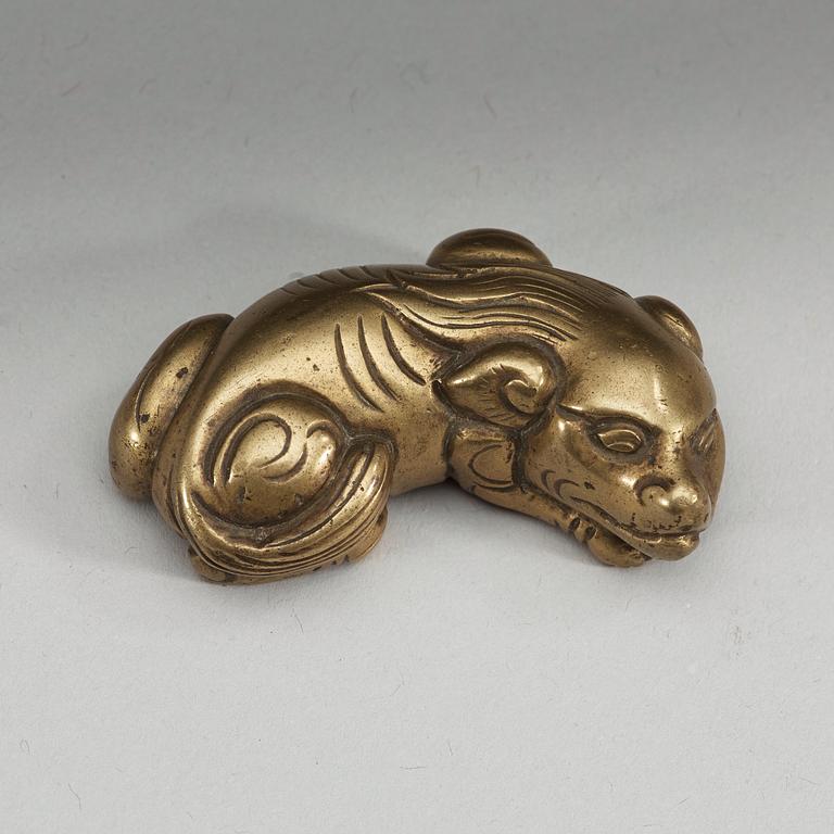 A bronze paper-weight modeled as a reclining lion, Qing dynasty, presumably 18th Century.