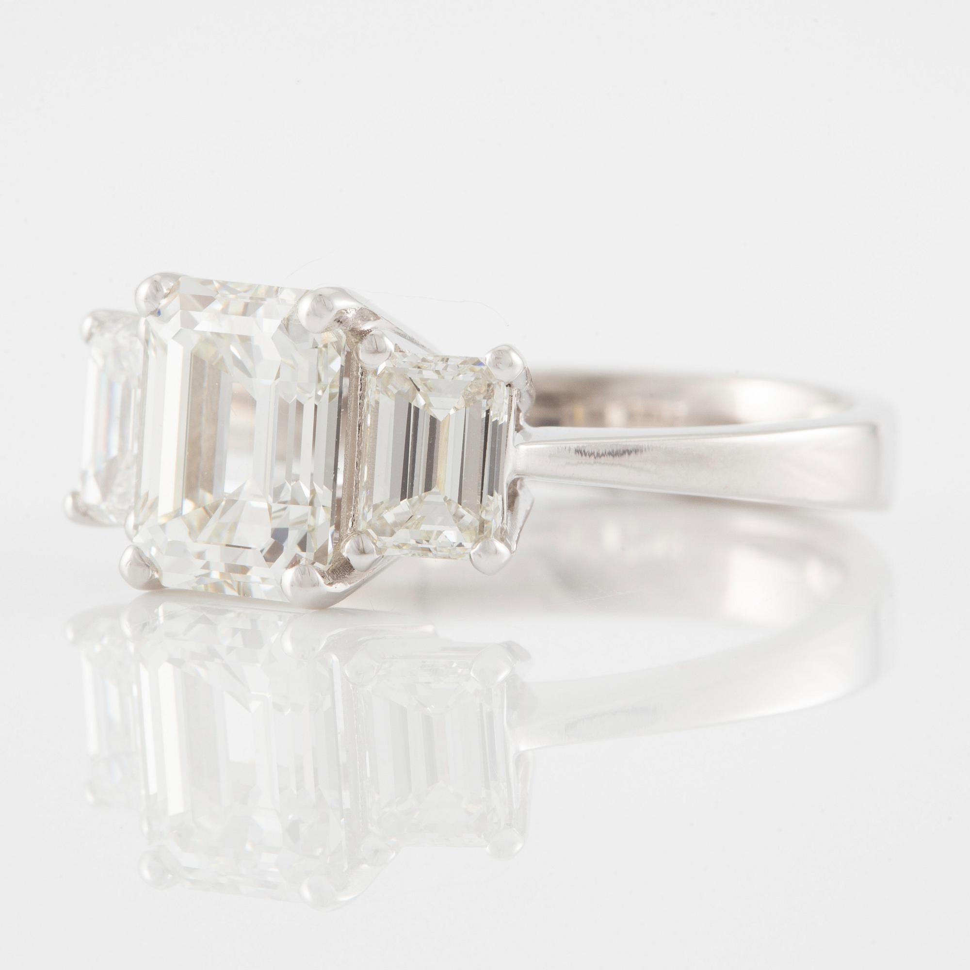 An 18K white gold ring set with three emerald-cut diamonds.