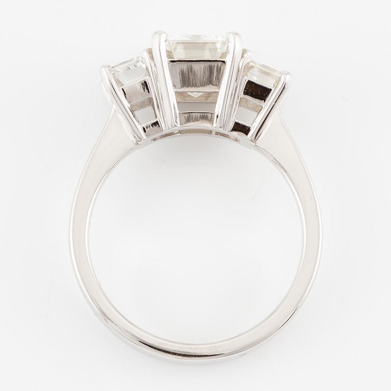 An 18K white gold ring set with three emerald-cut diamonds.