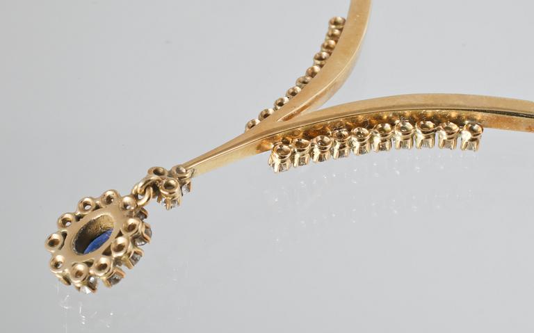 COLLIER, 18K guld med 33 briljantslipade diamanter samt ovalslipad blå safir. Vikt 32,4 gram.