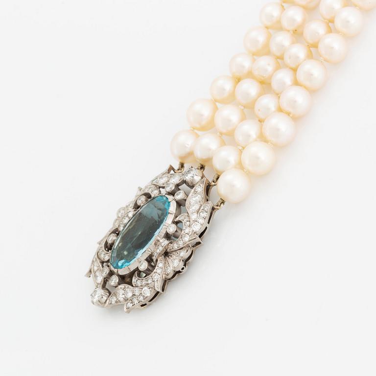 A four strand cultured pearl necklace with a clasp in 14K gold set with a faceted aquamarine.