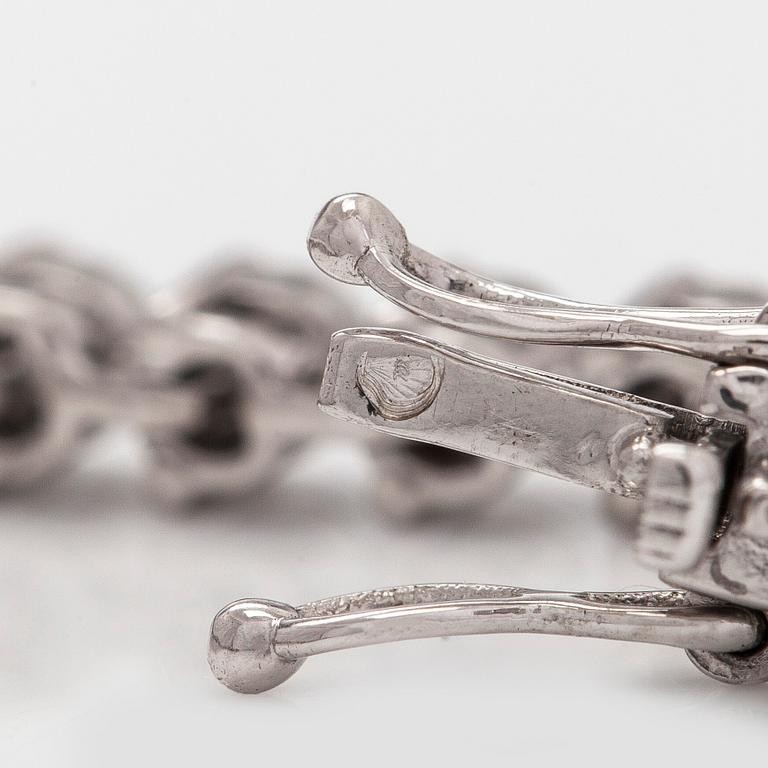 An 18K white gold tennis bracelet, with brilliant-cut diamonds.