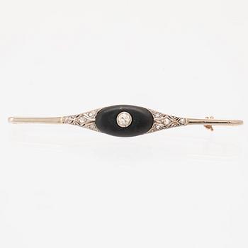 A 14K white and red gold brooch set with round brilliant-cut and rose-cut diamonds and a black stone.