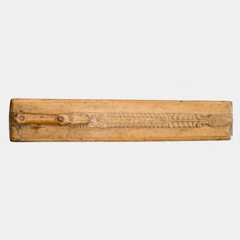 A Swedish folk art mangle board with carved decorationd, owners' initials and the date 1744.