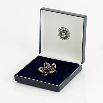 A silver and 14K gold brooch set with a blue stone and rose-cut diamonds.