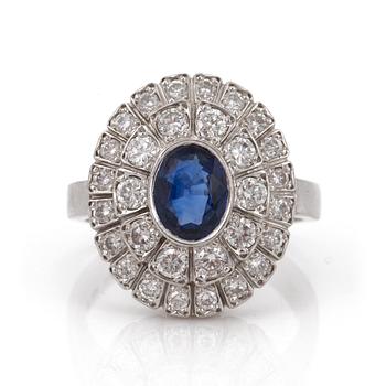 A ring set with an oval, mixed-cut sapphire and round, brilliant-cut diamonds.