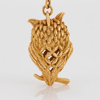 An 18K gold Hermès key chain in the form of an owl set with rubies.