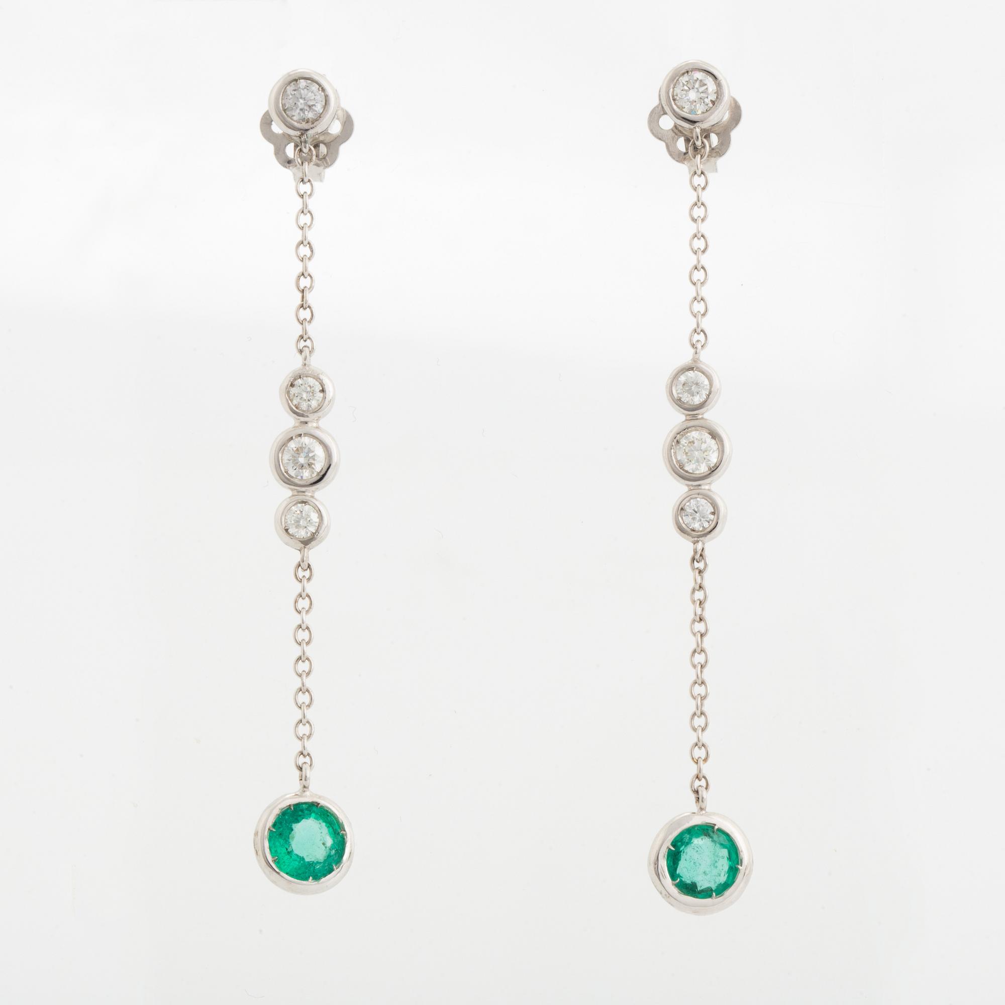 A pair of 18K white gold earrings set with faceted emeralds.