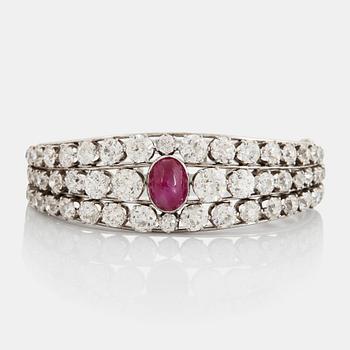 978. An 18K white gold bangle set with a cabochon-cut ruby and old-cut diamonds.