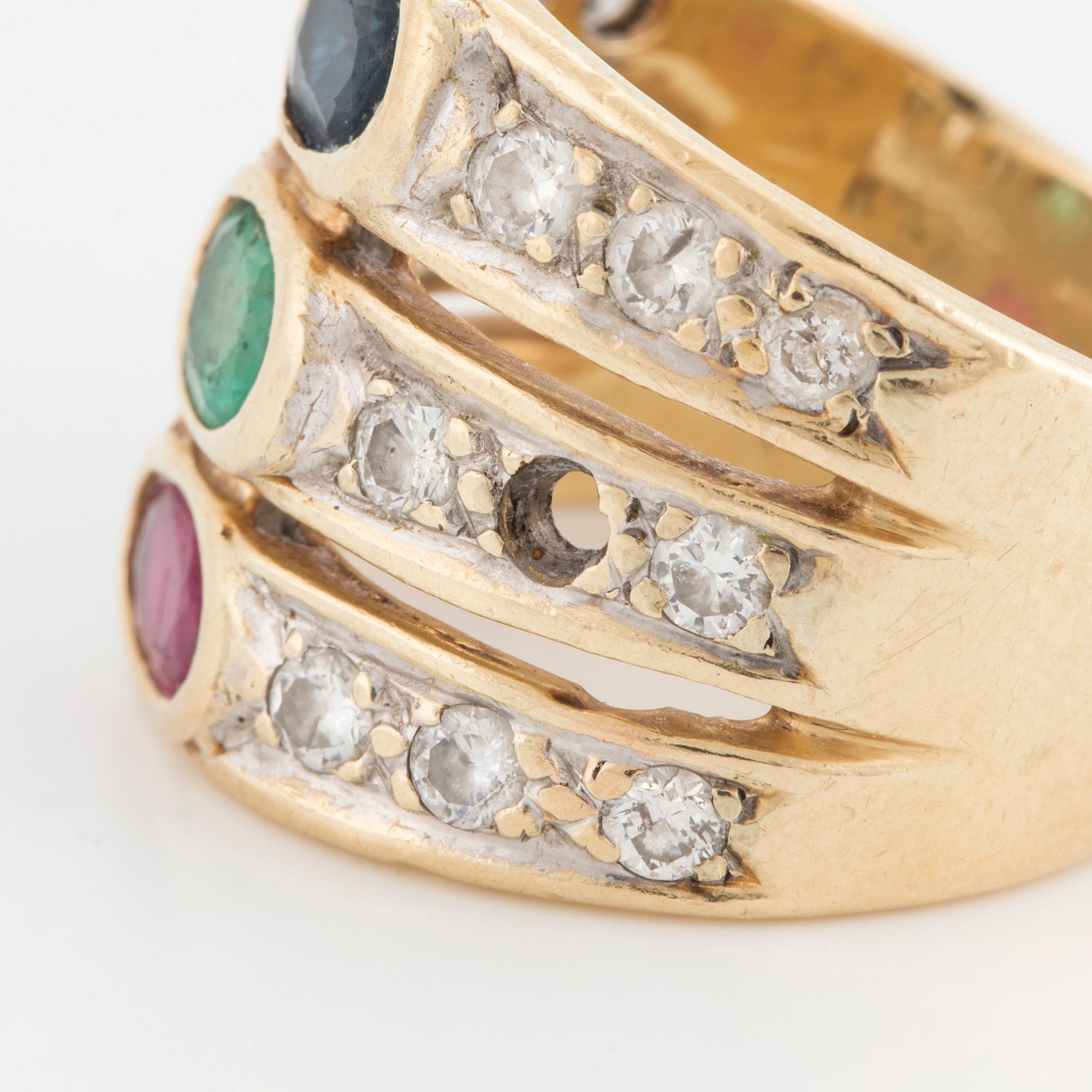 An oval cut ruby, sapphire and emerald ring, surrounded by brilliant cut diamonds.