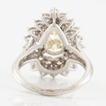 A platinum ring set with a pear-shaped yellow diamond and round brilliant-cut diamonds.