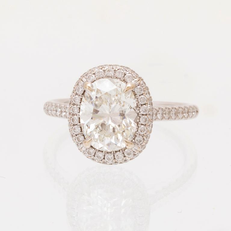 An 18K white gold ring by James Allen, set with an oval brilliant cut diamond in a halo of round brilliant cut diamonds.