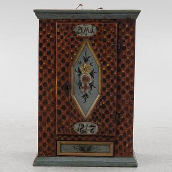 A painted wall cabinet, dated 1817.