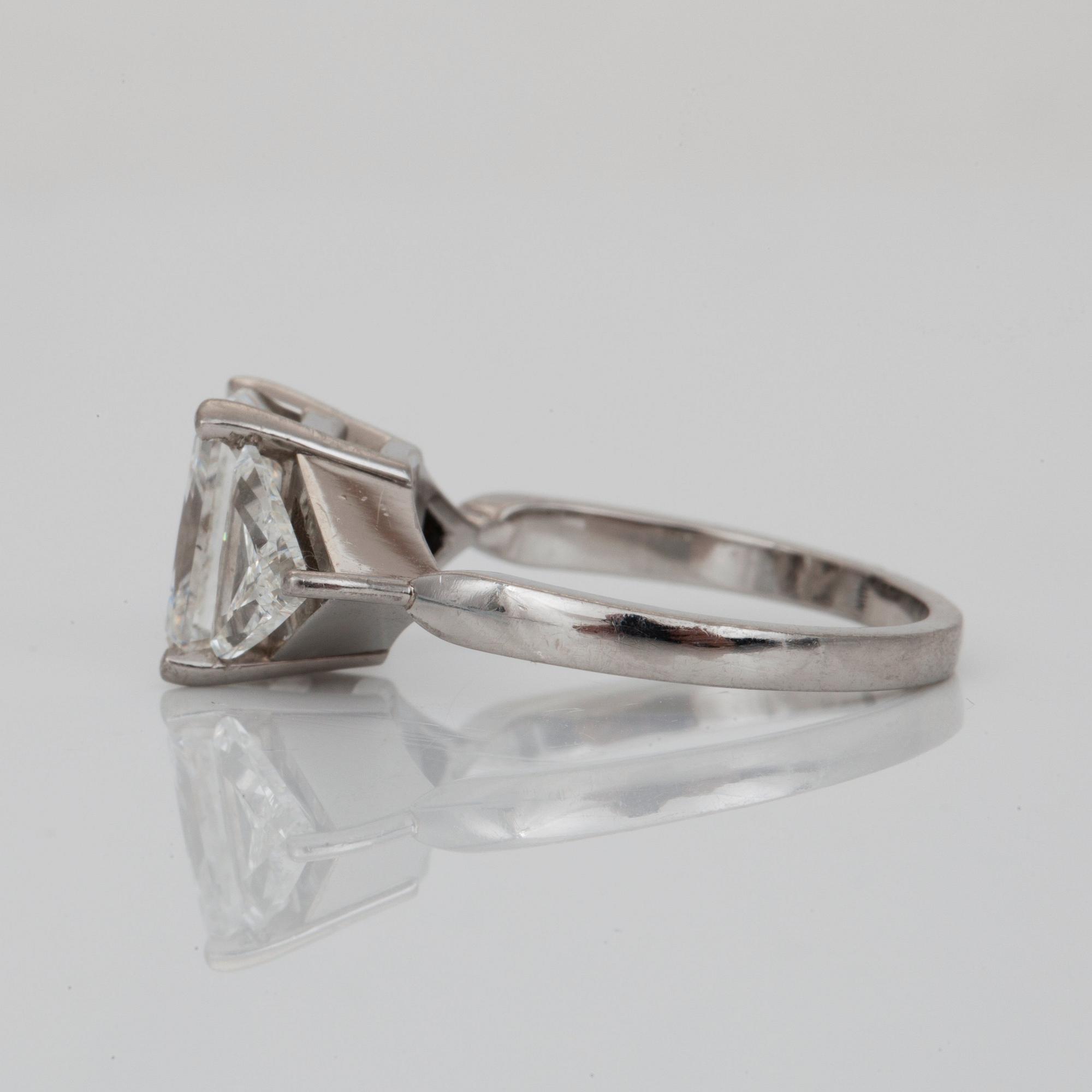 A radiant-cut diamond, 3.01 cts ring. Flanked by two triangular cut-diamonds, 0.50 ct each. E/VS2, certificate from HRD.