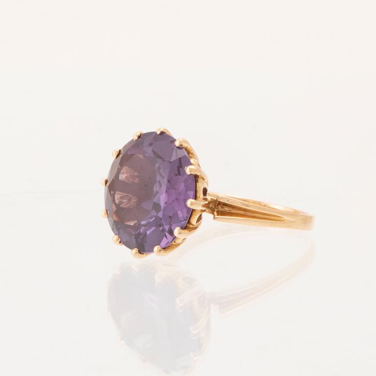 An 18K gold ring set with a round faceted colour-changing synthetic purple sapphire, Heribert Engelbert Stockholm.