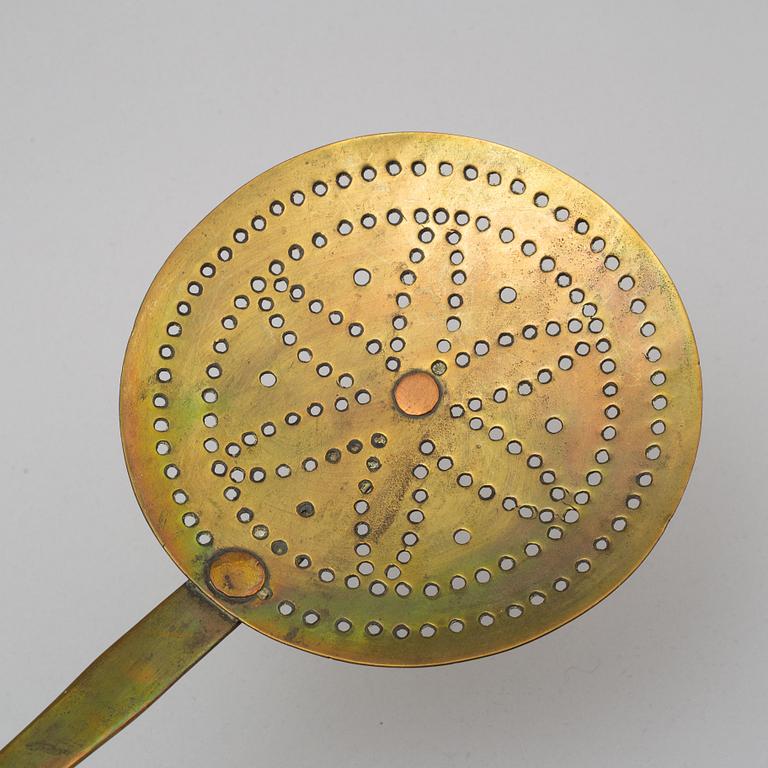 An 18th century brass strainer.