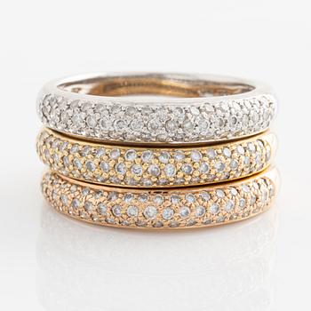 Three 18K gold rings with round brilliant-cut diamonds.