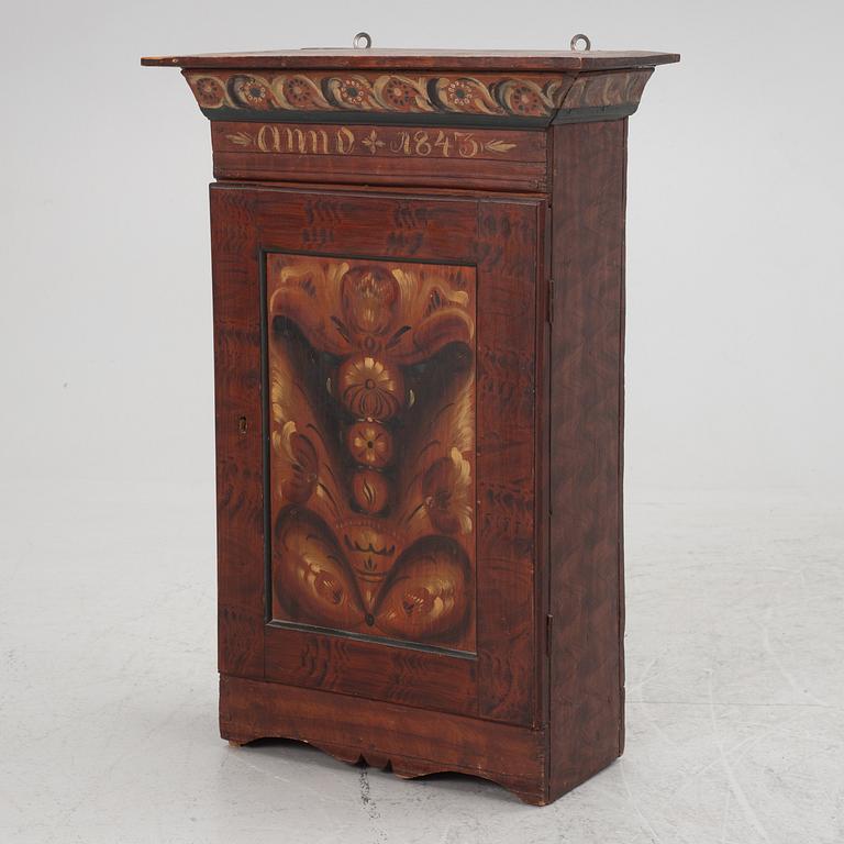 A wall cabinet, dated 1843.