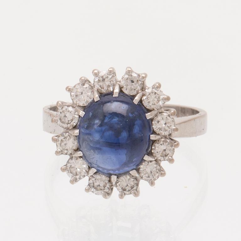 An 18K white gold ring set with a cabochon cut sapphire and round brilliant cut diamonds.