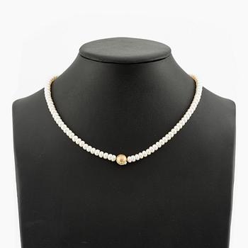 Ole Lynggaard clasp in 18K gold with a round brilliant-cut diamond and a freshwater cultured pearl necklace.