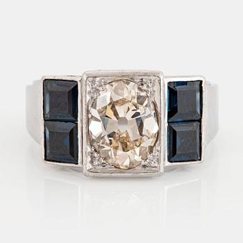 1121. An 18K white gold ring set with an old-cut dimond weight ca 1.50 cts and step-cut sapphires.