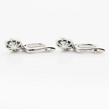 Ett par örhängen med fasettslipade smaragder och runda briljantslipade diamanter.
