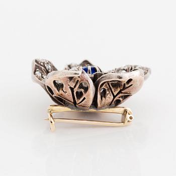 A silver and 14K gold brooch set with a blue stone and rose-cut diamonds.