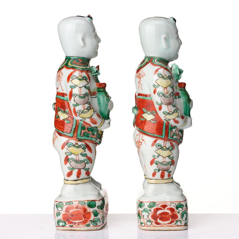 A pair of wucai decorated porcelain figurines of boys with flowers, Qing dynasty, Kangxi (1662-1722).