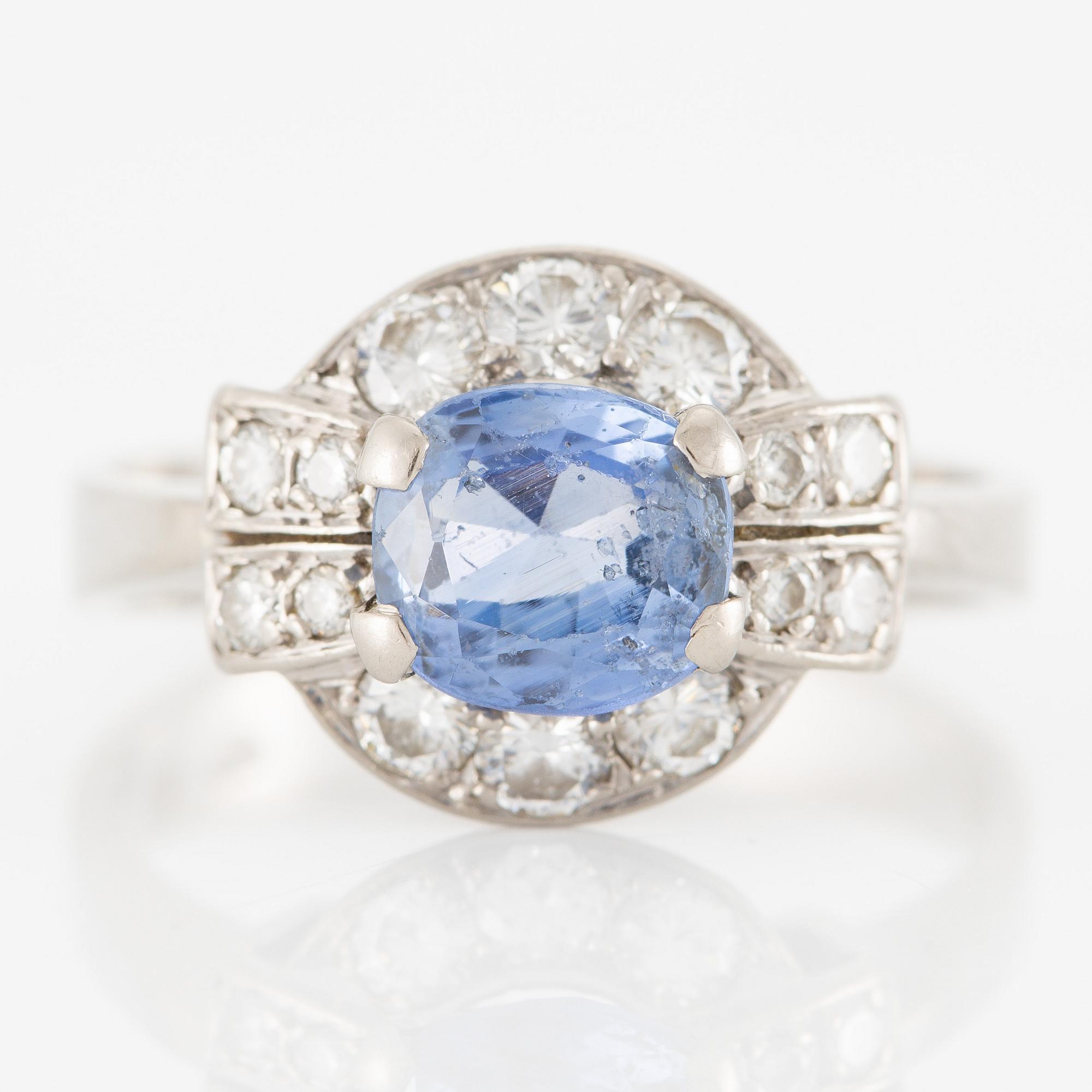 Ring 18K white gold set with a faceted sapphire and round brilliant-cut diamonds.