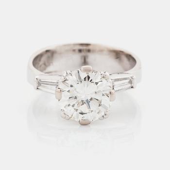 474. An 18K white gold ring set with a round brilliant-cut diamond and two tapered baguette-cut diamonds.