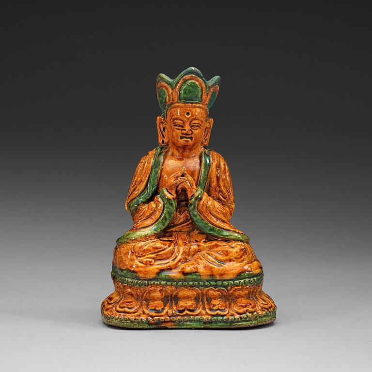 A yellow and green glazed pottery figure of a seated Buddha, Ming dynasty, 17th century.