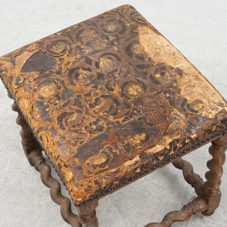 A turned oak Baroque style stool, 19thb Century, covered with older gilt leather.