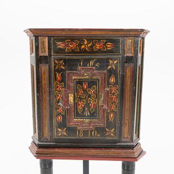 Corner cabinet on a legged stand dated 1810.