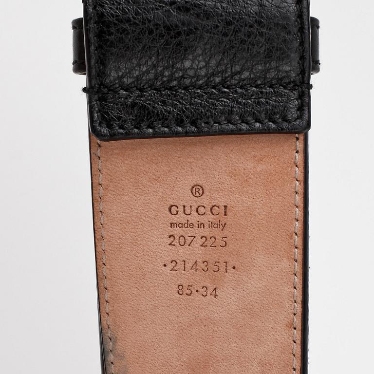 GUCCI, a black leather belt with goldcolored and patinated decor.