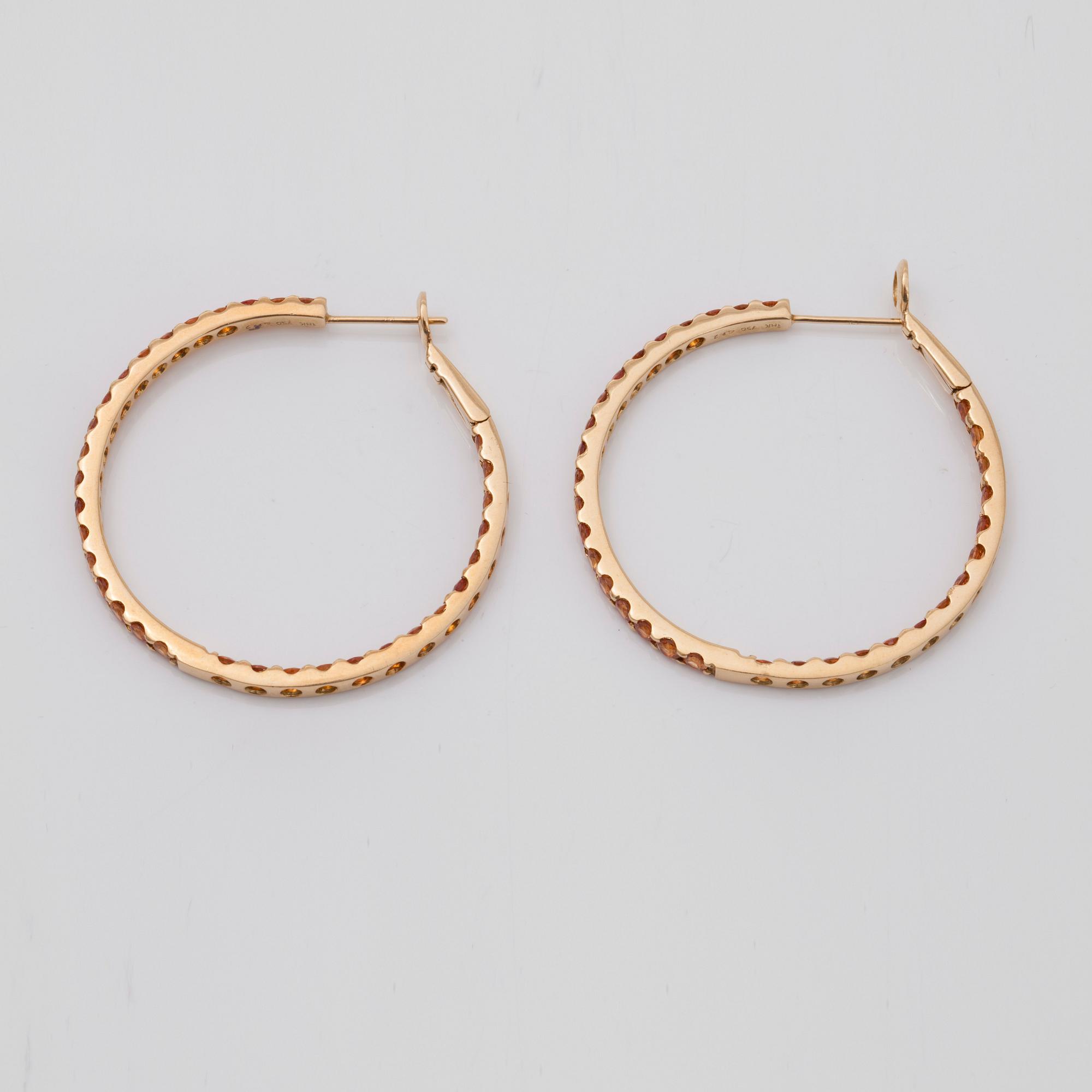 A pair of orange-yellow sapphire hoop earrings.