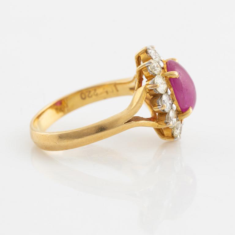 An 18K gold ring set with a cabochon-cut ruby and round brilliant-cut diamonds.